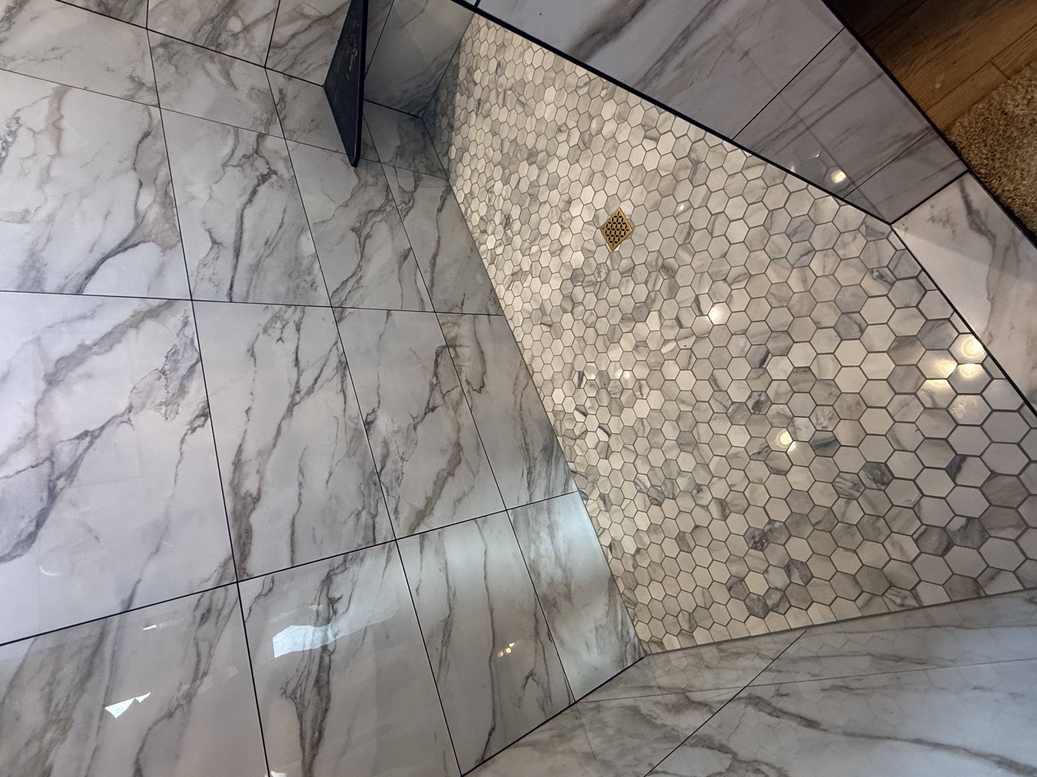 Marble-look tile shower with hex mosaic floor